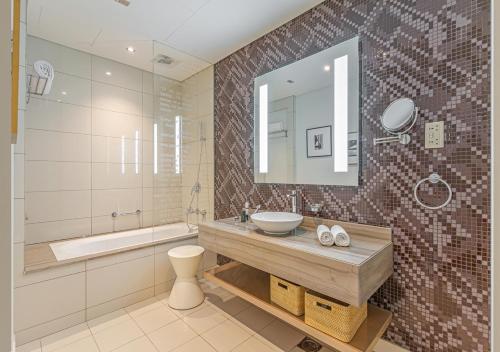a bathroom with a sink and a tub and a mirror at Savis Homes - Damac Paramount Tower A 1BR Ultimate Luxury and Glam Escape in Dubai