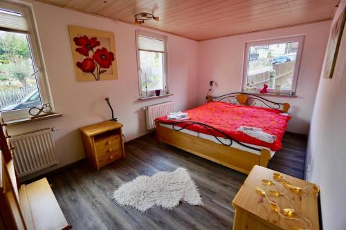 バート・ブリュッケナウにあるFerienwohnung Sonnenterrasseのベッドルーム1室(赤いベッド1台、窓2つ付)