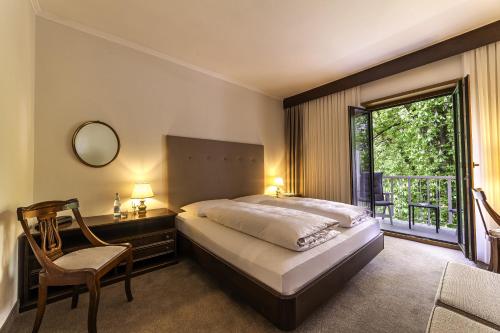 een slaapkamer met een bed, een raam en een stoel bij Hotel Isabella in Merano
