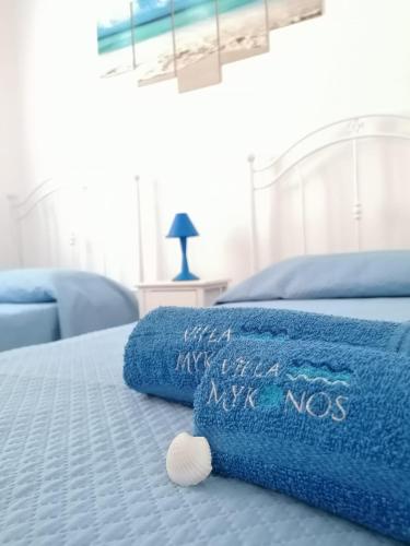 a bed with a blue blanket and a pillow with the words never nos at Villa Mykonos in Fontane Bianche