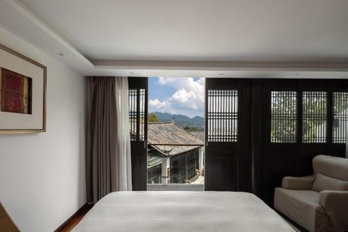 a bedroom with a bed and a couch and a window at 丽江山之名·音糖·大美华宿（束河古镇店） in Lijiang