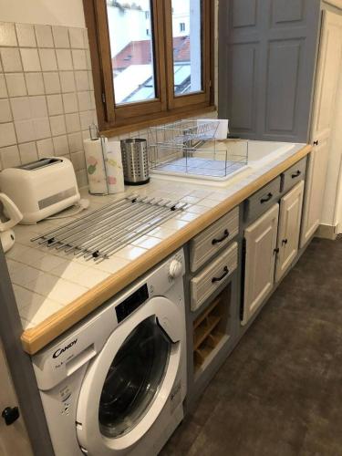 une cuisine avec une machine à laver sous un comptoir dans l'établissement Pétillant cosy, à Reims