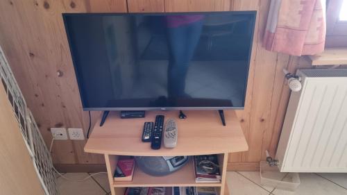 La BrévineにあるStudio à la fermeのリモコンが2つ付いたスタンドの上のテレビ