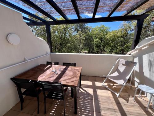 a wooden table and chairs on a balcony with a pergola at Charmant appartement Village Restanques de Saint Tropez in Grimaud