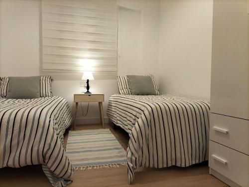 two beds in a room with a lamp on a table at 3 Bed Flat - Sleeps 5 - Wifi in Bellreguart