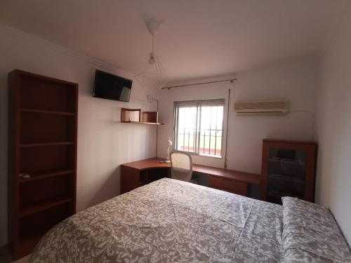 a bedroom with a bed and a desk and a window at MRZ RENTALS JEREZ in Jerez de la Frontera