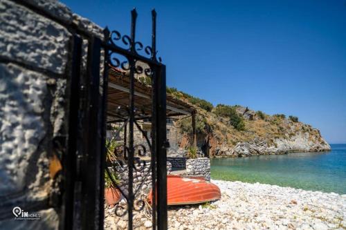 a fence on a beach with a boat in the water at Faskomilo Stone House On The Beach in Khalíkia