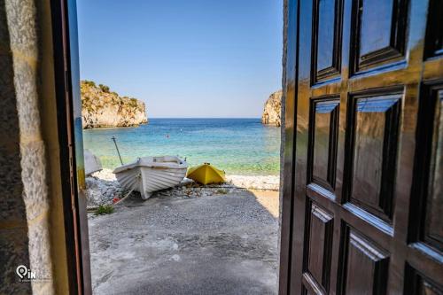 a view of a beach with a boat and the ocean at Faskomilo Stone House On The Beach in Khalíkia
