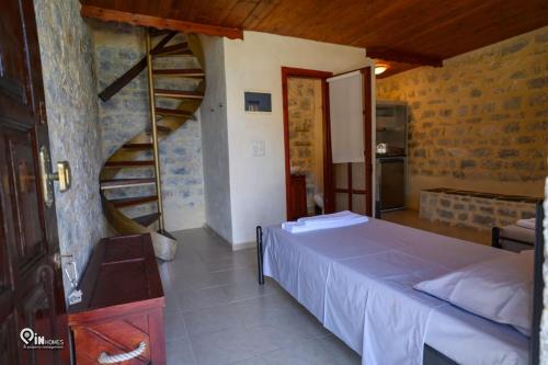 a bedroom with a bed and a spiral staircase at Faskomilo Stone House On The Beach in Khalíkia