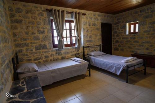 two beds in a room with two windows at Faskomilo Stone House On The Beach in Khalíkia