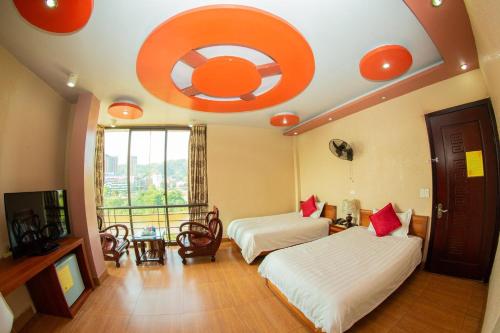 Zimmer mit 2 Betten und einer Decke mit orangefarbenem Ziel in der Unterkunft Vân Hà Hotel Lào Cai - by Bay Luxury in Lào Cai