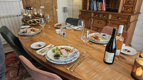 a wooden table with plates of food and wine glasses at L'Arc en Ciel in Bleurville