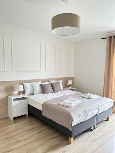 biała sypialnia z dużym łóżkiem i lampką w obiekcie Rezydencja Leśniów w mieście Żarki