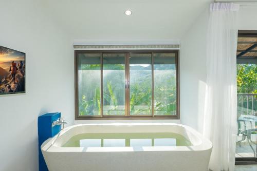 uma banheira branca num quarto com uma janela em KRAAM Silhouette Hotel and Cafe Phuket em Chalong