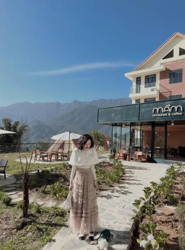 a woman in a dress standing in front of a building at Sapa Yen Hotel in Sa Pa