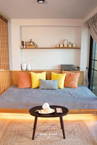 a bed with orange and yellow pillows and a table at Ayla Chalet in Phrae