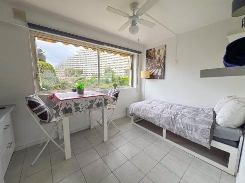 Un dormitorio con un escritorio y una cama y una ventana. en La Studette Marina 06, en Villeneuve-Loubet