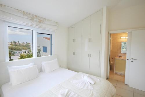 Un dormitorio blanco con una cama blanca y una ventana. en Serifos Villa 7 - 100 meters from Malama Beach, en Protaras