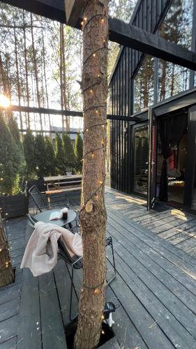 a tree on a deck with a chair next to it at Domek SzumiSosna2 in Życiny