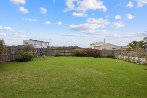 a yard with a playground and a fence at Island Daze Surf Beach Phillip Island in Phillip Island