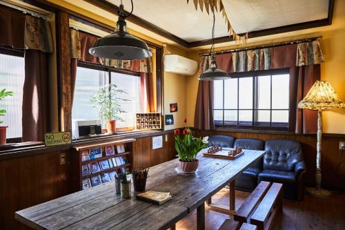 Cette chambre dispose d'une table en bois, de chaises et de fenêtres. dans l'établissement ソルトハウス, à Imabari