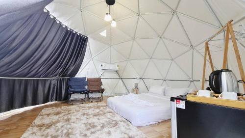 a room with a tent with a bed and two chairs at Greatland Glamping Khao Yai Resort in Ban Khanong Phra Tai