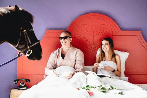 a man and a woman sitting in a bed at Schwarzes Rössl in St. Wolfgang