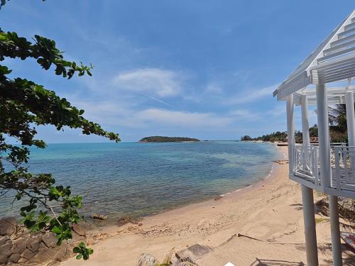 a view of a beach with a white chair at Bhundhari Resort & Villas Samui in Chaweng
