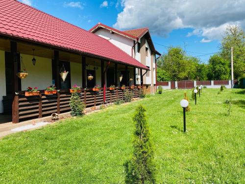 a house with a red roof and a green yard at Serenity Garden Villa in Runcu