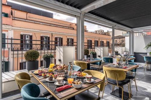 ein Restaurant mit Tischen und Stühlen sowie Speisen auf dem Balkon in der Unterkunft CC Palace Hotel in Rom