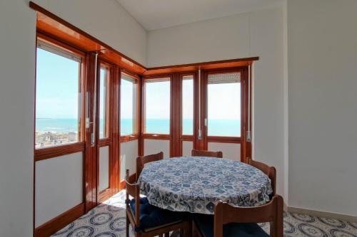 a dining room with a table and some windows at Mare Fuori in Nettuno