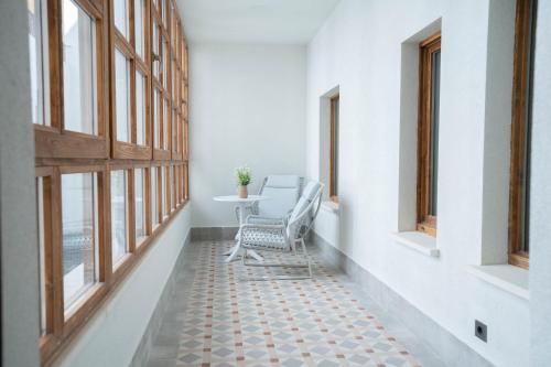 pasillo con mesa, silla y ventanas en Prisma Suites en Salamanca