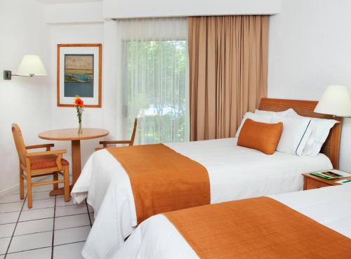 a hotel room with two beds and a table at Hotel Viva Villahermosa in Villahermosa