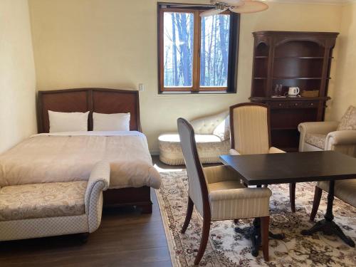 a bedroom with a bed and a table and chairs at ヴィラカーサビアンカ八ヶ岳 in Hokuto