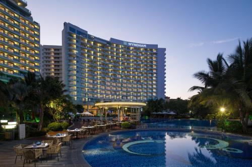 a hotel with a swimming pool in front of a building at Ramada Plaza by Wyndham Sanya Bay in Sanya
