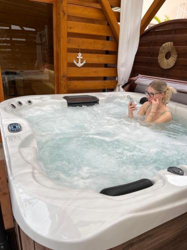 a woman sitting in a jacuzzi tub at Gabi Apartmanház in Balatonlelle