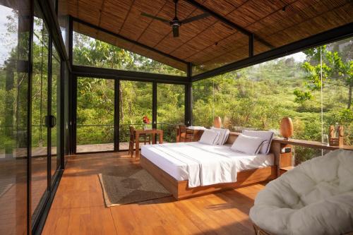 a bedroom with a bed in a room with glass walls at Kurunduketiya Private Rainforest Resort in Kalawana