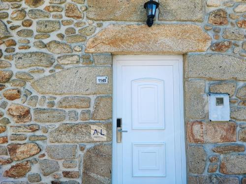 una porta bianca in un edificio in pietra con un muro di pietra di Casinha do Sossego a Melgaço