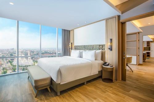 a bedroom with a large bed and large windows at Swiss-Belhotel Solo in Solo