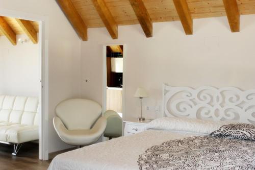 een witte slaapkamer met een bed en een stoel bij Complejo Rural La Coronilla in Jarandilla de la Vera
