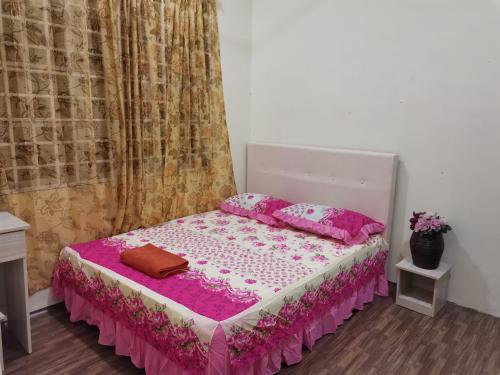 um quarto com uma cama com lençóis e almofadas cor-de-rosa em Jalinan Qaseh Homestay em Seri Manjung