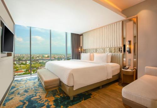 a bedroom with a large bed and a large window at Swiss-Belhotel Solo in Solo