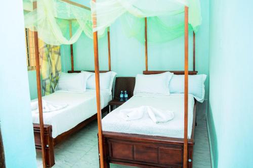 2 łóżka pojedyncze w pokoju z lustrem w obiekcie NB MOTEL-KIHIHI w mieście Kihihi