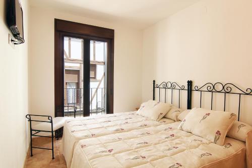 a bedroom with a bed and a chair and a window at Hostal Yessy in Candeleda