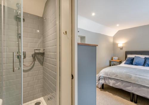 a bathroom with a shower and a bed in a room at Fern Lea in Brancaster