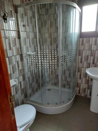 a bathroom with a shower with a toilet and a sink at Résidence beau-lieu in Yaoundé