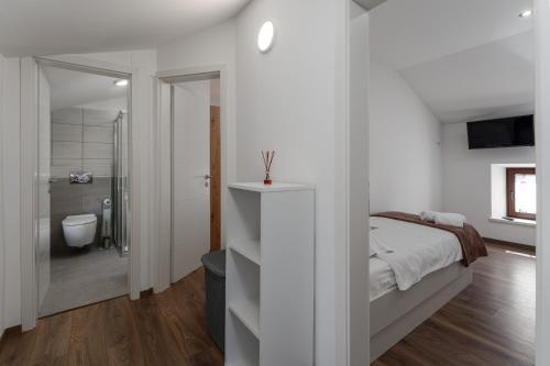 ein weißes Schlafzimmer mit einem Bett und einem Badezimmer in der Unterkunft Rustic Villa Stone House with pool in Umag in Čepljani