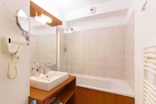 uma casa de banho com um lavatório, um chuveiro e um espelho. em Le Jouarres - Appt climatisé avec piscine partagée em Azille