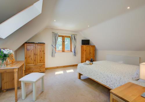 Schlafzimmer mit einem Bett, einem Schreibtisch und einem Fenster in der Unterkunft Ruston Lodge in Thursford