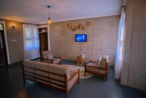 uma sala de estar com um sofá e cadeiras e uma televisão em Boloti Camp resort em Lemira